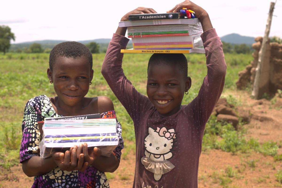 Two girls carrying new school books and supplies in Togo